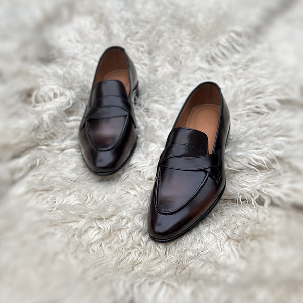 Andrew - Single component penny loafer with an elegant twisted leather tie on the facing. Hand made from the finest Calf leather with hand-stitch detailing. Soft inner naturally tanned cow leather lining. Rounded edge vegetable tanned leather sole. Finished in the very beautiful Hazelnut patina.