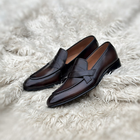 Andrew - Single component penny loafer with an elegant twisted leather tie on the facing. Hand made from the finest Calf leather with hand-stitch detailing. Soft inner naturally tanned cow leather lining. Rounded edge vegetable tanned leather sole. Finished in the very beautiful Hazelnut patina.