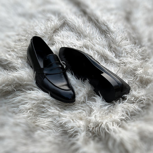 Andrew - Single component Penny loafer, made from the finest black calf leather with hand stitch detailing. The facing is adorned with a beautiful twisted leather tie, offering effortless elegance & panache