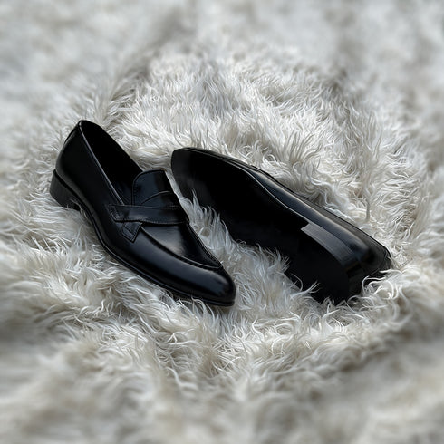 Andrew - Single component Penny loafer, made from the finest black calf leather with hand stitch detailing. The facing is adorned with a beautiful twisted leather tie, offering effortless elegance & panache