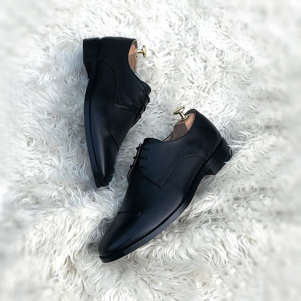 Logan - Two component derby with single vamp and pseudo cap toe with slit detailing. Made from the finest black calf leather, soft inner crust leather lining and full welted leather sole + full stacked leather heel.
